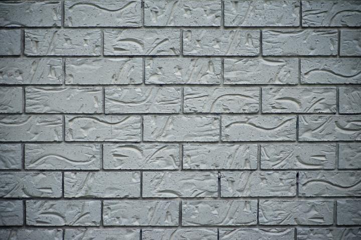 Decorative grey brick background of incised and patterned grey bricks in a neat wall construction, full frame, pattern and texture
