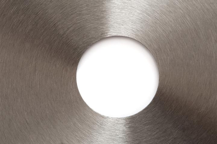 A close up of a metal, stainless steel saw blade and center circle with white copy space in the middle.