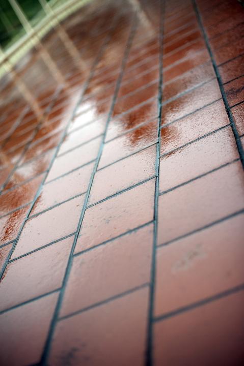Wet red terracotta tiles outdoors on a rainy day viewed at an angle with reflections