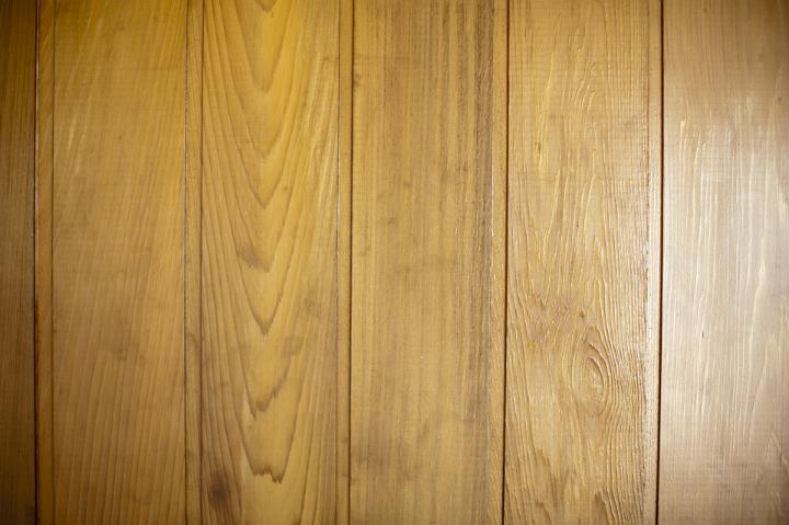 Brown polished wood panelling made of horizontal wall mounted battens, close-up