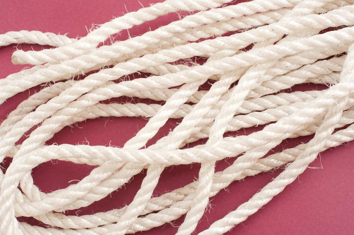 Close up Long Coiled White Rope on a Dark Pink Background