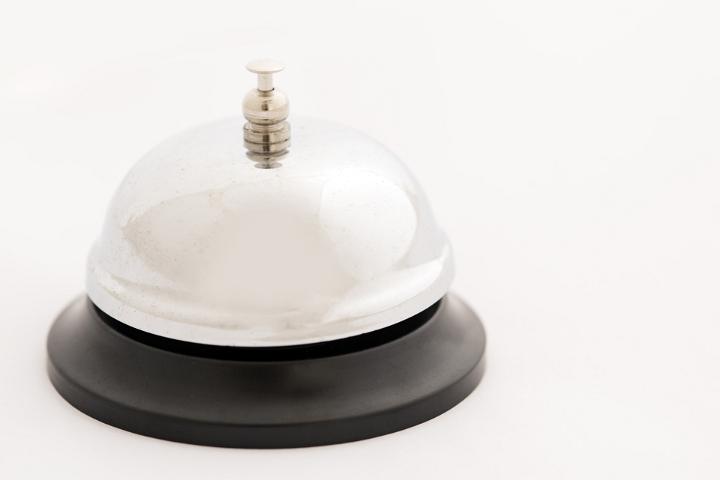 Close up of a silver metal hotel service bell isolated on a plain white background with copy space.