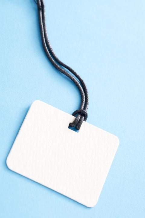 Close up of an empty white name tag table and string lanyard isolated on a plain blue background with copy space.