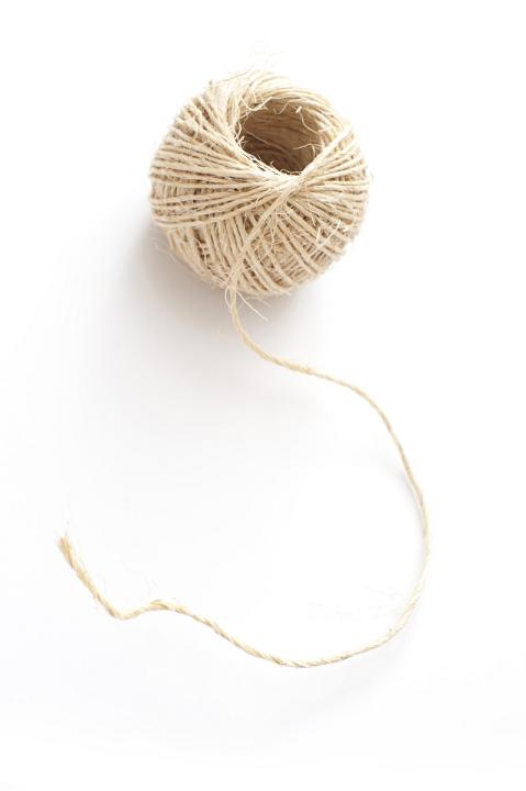 Ball of household string or twine made from hemp fibres on a white background, high angle