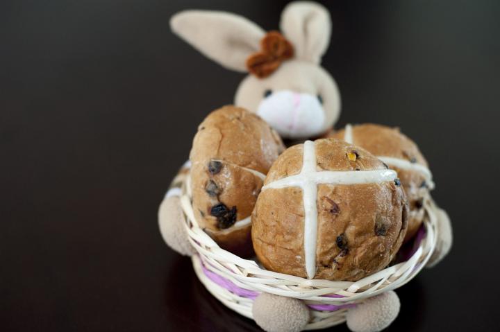 Easter baking concept with delicious fresh fruity Hot Cross Buns displayed by an Easter Bunny in a basket