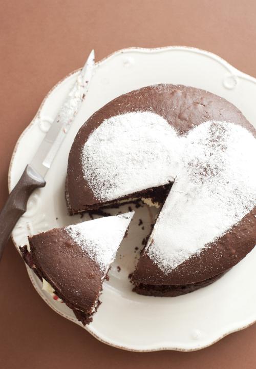 Overhead view of a single slice cut from a fresh chocolate cake decorated with an icing sugar heart served on a plate
