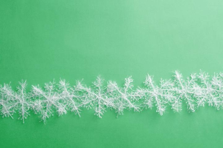 Decorative white Christmas snowflake wreath isolated on a plain green background.