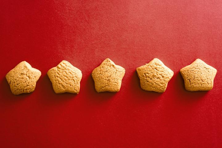 Five home baked star shaped cookies on a plain red background with copy space.