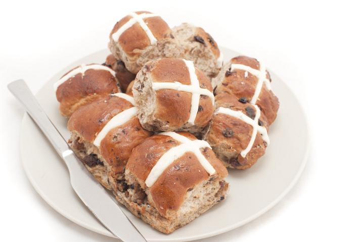 Plate of freshly baked spicy fruity Hot Cross Buns with raisins symbolic of the crucifixion of Christ at Easter