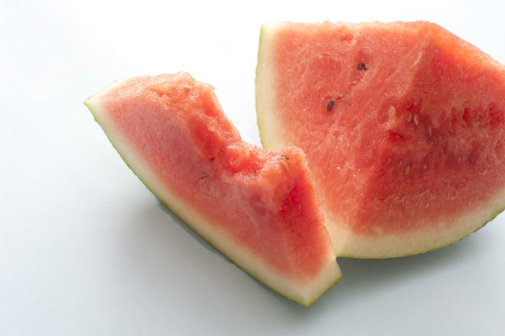 Half eaten slice of fresh juicy watermelon over a white background for a healthy refreshing summer snack