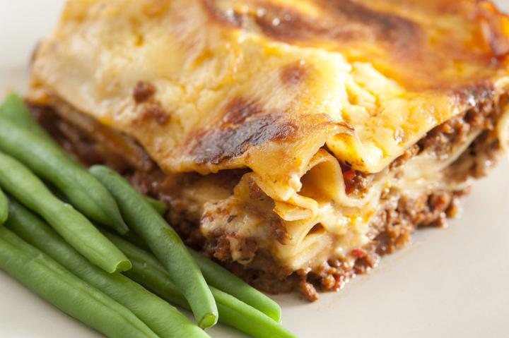 Close Up of Meal of Baked Lasagna Served with Green Beans on Plate for Dinner