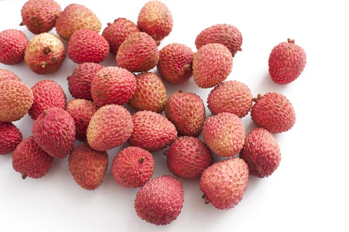 Assortment of Lychee Fruits in Pink and Red Rinds on White Background
