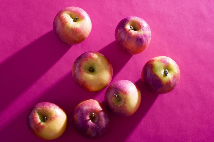 Seven fresh apples lying on purple background