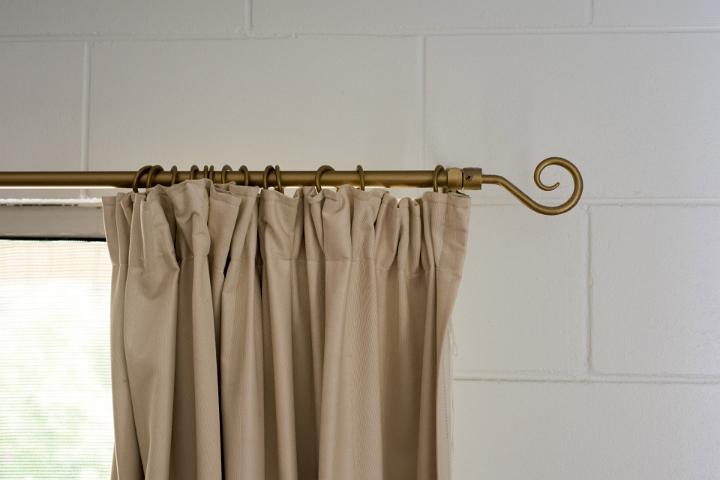 Beige window curtain hanging from decorative rod