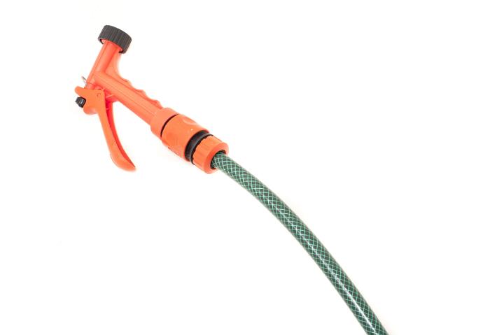 Plastic garden hose and orange nozzle for spraying and watering plants isolated on a white background