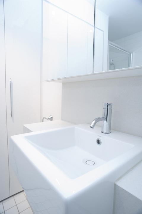 Modern rectangular white hand basin with a mixer tap in a white bathroom interior with mirror and cabinets
