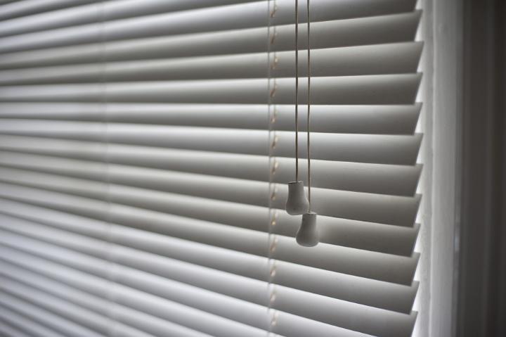 Horizontal venetian blinds in the closed position with the two toggles in the foreground, oblique angle view
