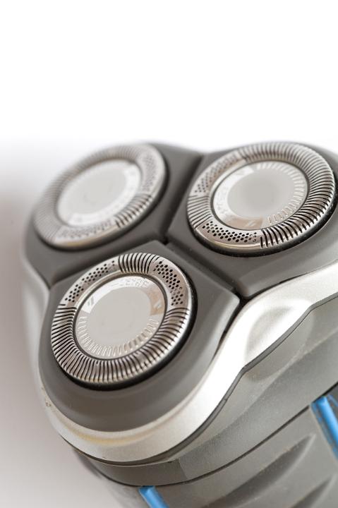 Head of an electric shaver with three circular blades showing close up detail with white copyspace above