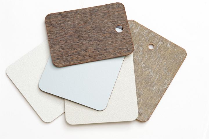 Pile of different neutral colored laminate swatches for interior coverings and surfaces in a house lying on top of each other on a white background