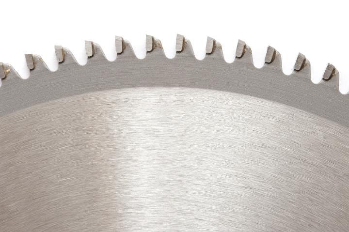 Close up of the teeth on a metal circular saw blade isolated on a white background with copy space.