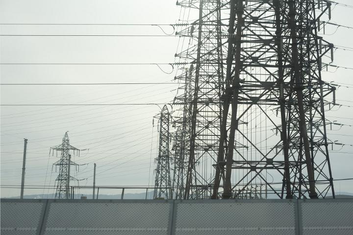 Group of large steel lattice power pylons supplying industry with electricity viewed on a grey misty day