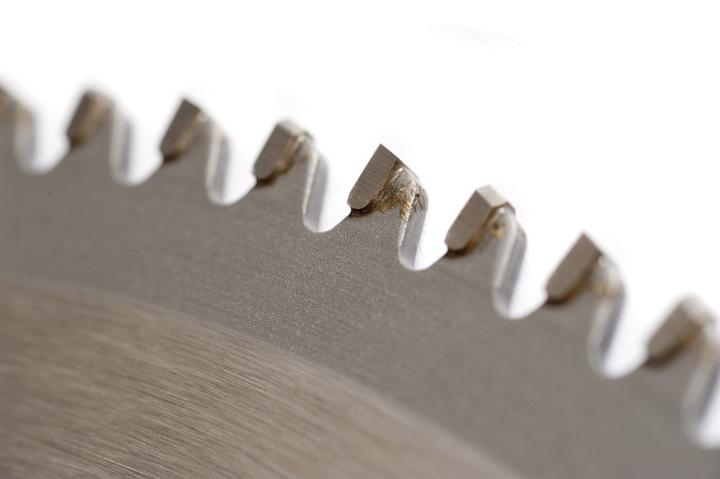 Detail of the sharp steel teeth on a new circular saw blade for woodworking isolated on white in a partial view