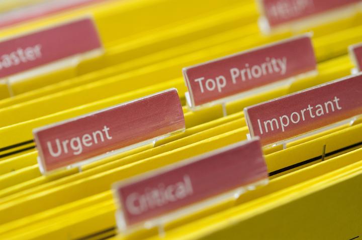 Busy Concept - Close up Yellow Folders with Labels Emphasizing Urgent, Critical, Important and Top Priority Keywords.