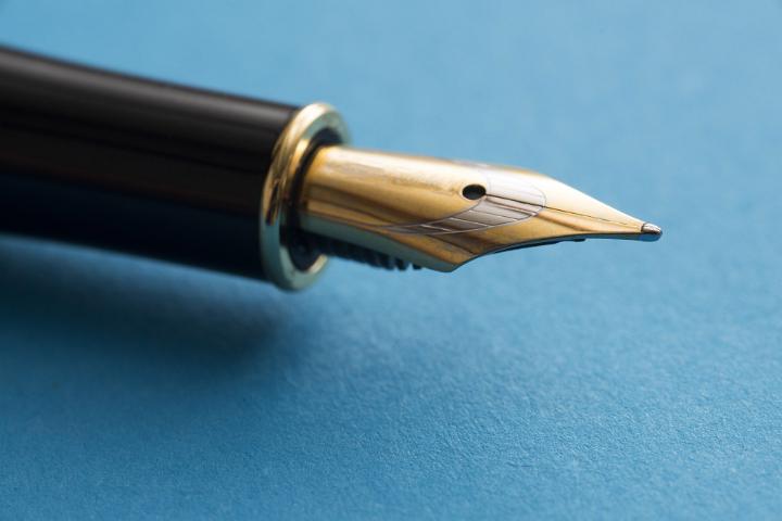 Gilded pen nib in close-up view against blue background