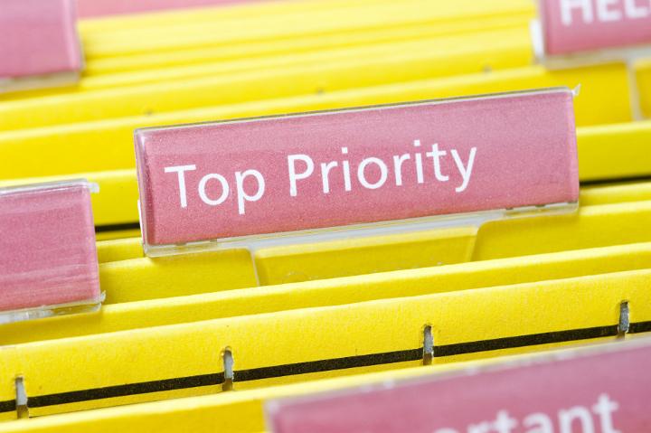 Priority Task Concept - Close up Yellow Folders with Pink Labels, Emphasizing Top Priority.