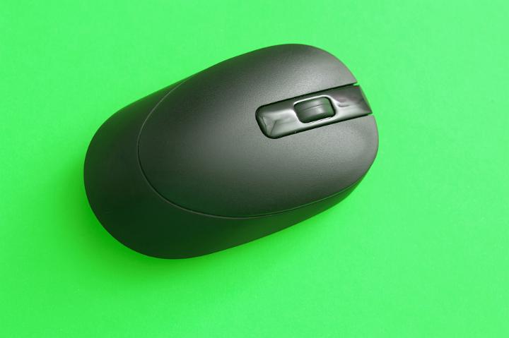 Close up Black Wireless Computer Mouse Isolated on Green Background, Emphasizing Copy Space.