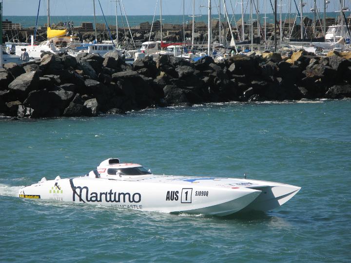 A competitor in power boat racing idling his speedboat in front of a harbor wall as he waits for his race