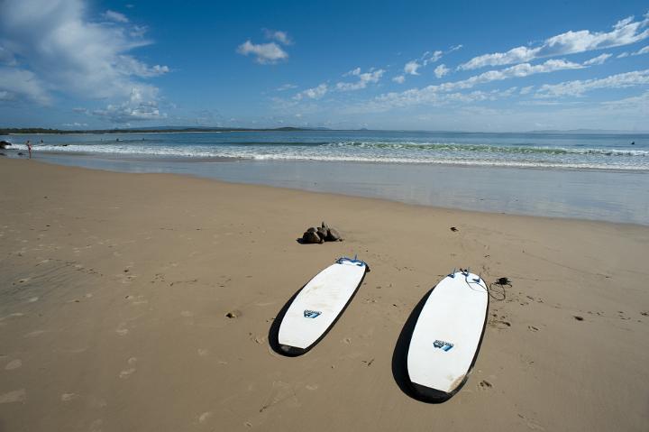 Surfing on a tropical beach concept with two surfboards left lying on the wet sand in front of a calm ocean, with copy space