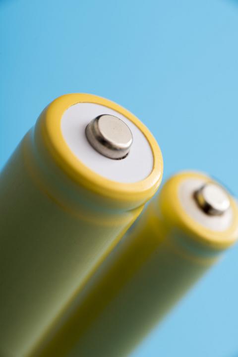 Close up view of the positive terminal on a rechargeable battery over a blue background in a power and energy concept