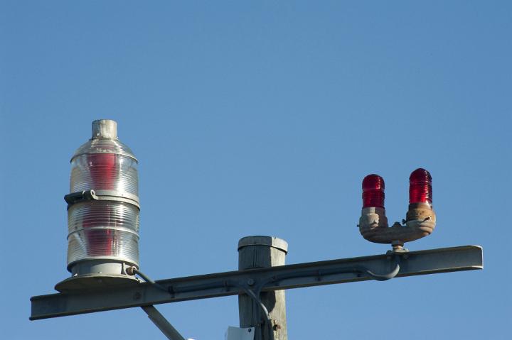 Close Up of Warning Lights and Directional Guiding Beacons for Airplanes on Top of Post at Airport with Clear Blue Sky in Background