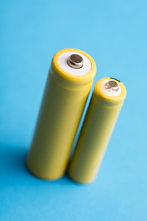 Two yellow baterries in different sizes standing on blue background