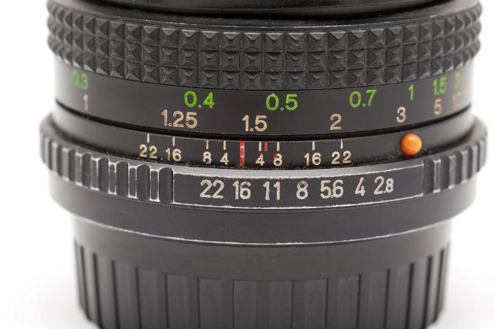 Close Up of Manual SLR Camera Lens with Aperture and Focal Length Setting Numbers in front of White Background