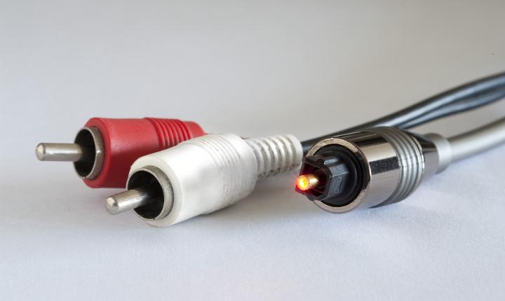Plugs of three copper optical cables, red, white and silver, close up on gray, concept of high technology