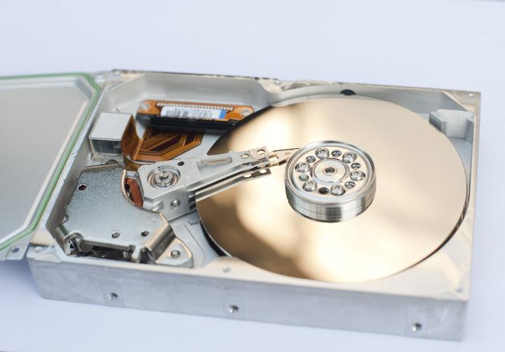 Close Up of Gold Colored Disk and Motor Hub of Hard Drive Computer Component on White Background