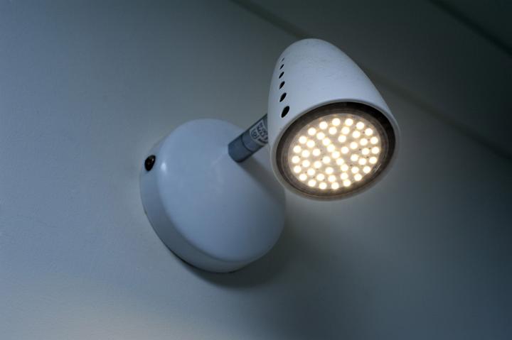 An downlight with illuminated LED's mounted on a white interior home wall.