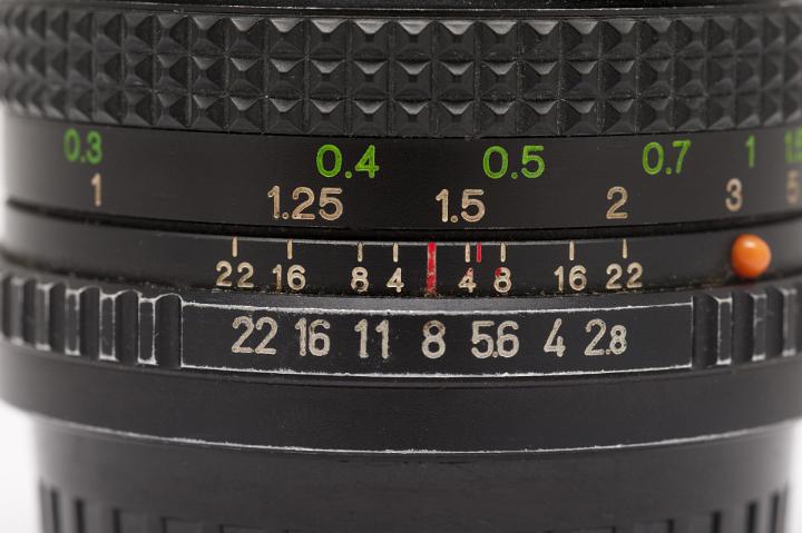 Old Slr camera lens showing focal length, aperture and metering options on the ring dials on the body