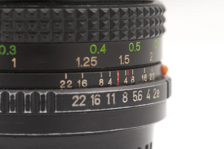 Close Up of Manual SLR Camera Lens Showing Aperture Readings and Focal Length with Copyspace on White Background
