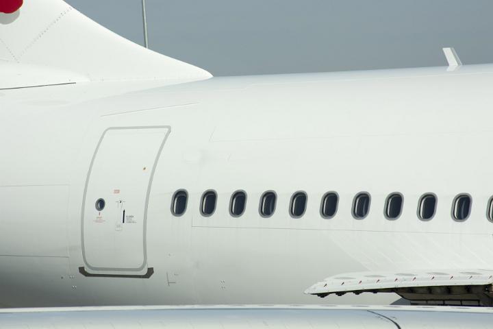 A close up of passenger windows and exit door on a large commercial airline plane.