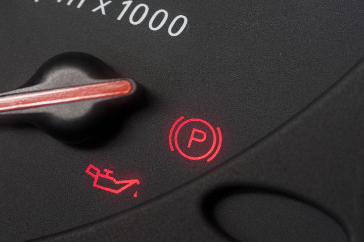 Close Up of Red Illuminated Oil and Parking Warning Lights on Car Dashboard Display