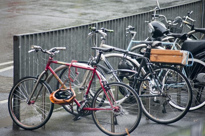Various bicycles parked and chained at a city street bike rack.