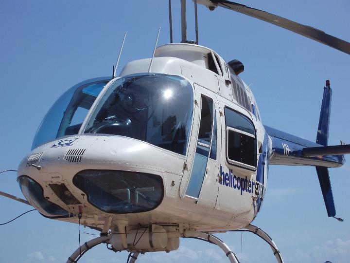 Close up then body of a white helicopter with the cockpit and windshield against a clear sunny blue sky