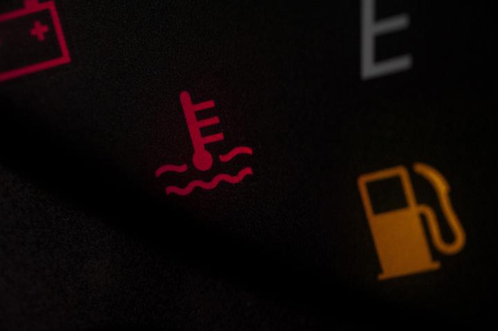 Low fuel warning light in a car illuminated on the dashboard together with a temperature waning
