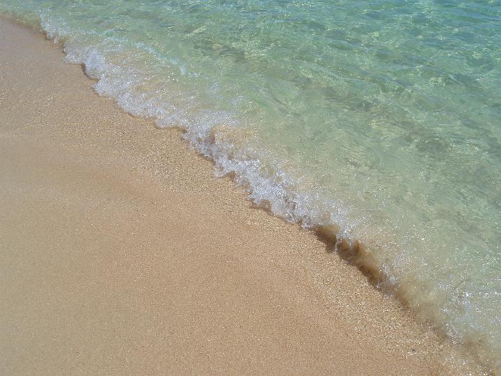 Calm sea lapping onto a tropical beach with golden sand conceptual of travel and summer vacations