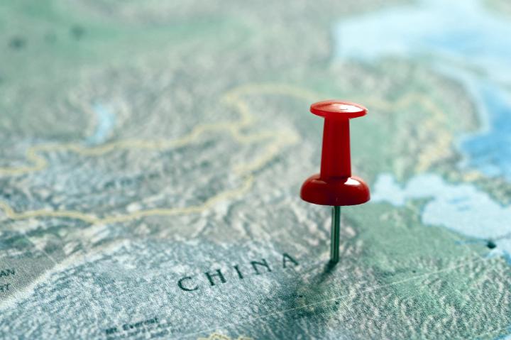 Close Up of Red Thumb Tack Pinned into Map of China as Location Marker