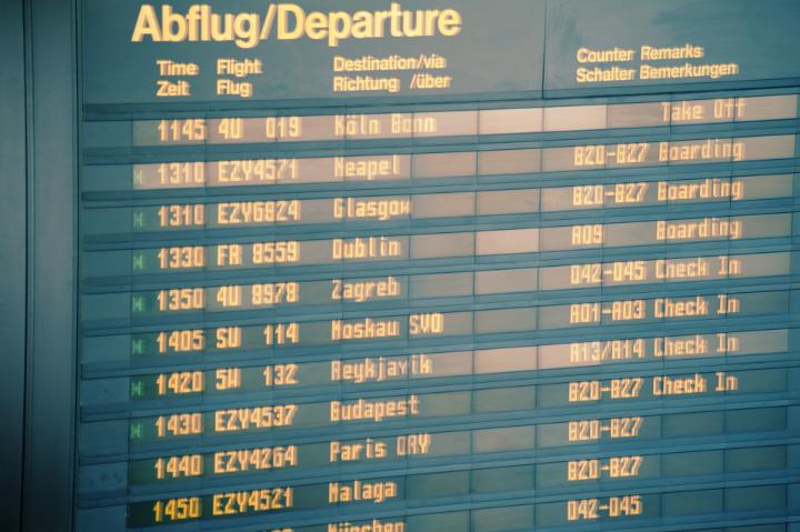 Departures sign board with flight details and times at an airport terminal, close up view conceptual of travel and tourism