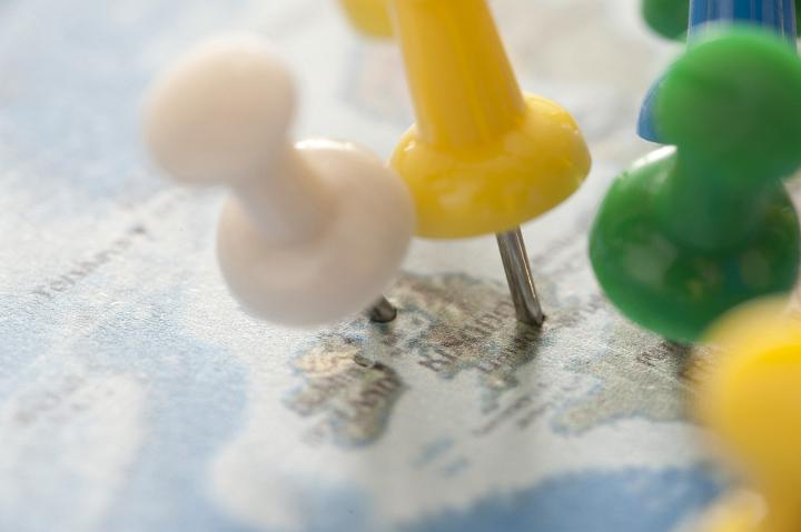 Close Up of Colorful Thumb Tacks Pinned into Various Locations on United Kingdom Map for Trip Planning